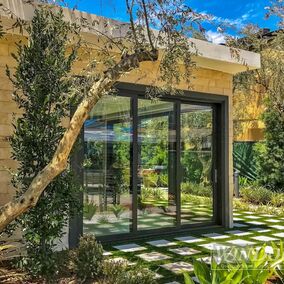 Windsor Systems sliding glass doors opening to a modern outdoor garden space with lush greenery and stone patio