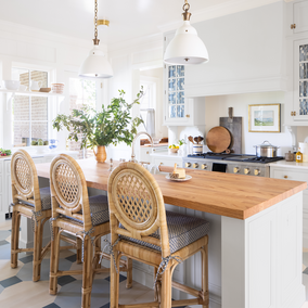 White kitchen featuring an island, blue accents, and wicker bar stools.