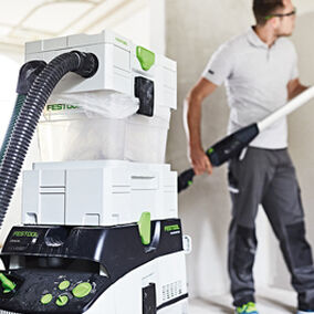 Construction worker operating a festool cyclone sander on drywall