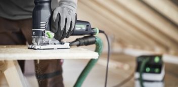 Worker using a Festool jigsaw for precision cutting on a construction project