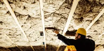 Construction worker installing energy efficient Knauf insulation in a ceiling