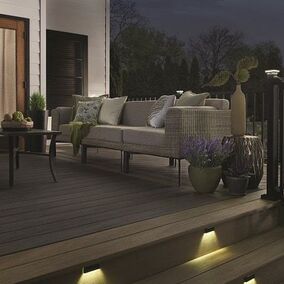 Wolf serenity walnut decking with lighting, black railing, in the backyard of a home