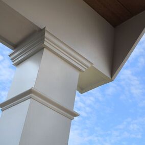 A versatex versawrap crown moulding installation on a front porch, showing moulding details and set against a blue sky background