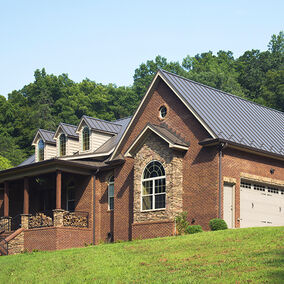 Central States Mfg metal roofing on a brick home with a wraparound porch and stone accents