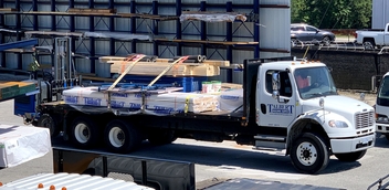 Talbert Building Supply truck loaded with lumber and construction materials, featuring a forklift attached for efficient unloading