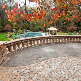 Beautiful outdoor area featuring Grotto Hardscapes with a curved stone wall and scenic landscaping